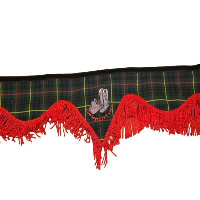 A distinctive truck pelmet featuring a cowboy boots design and “Cowboys don’t care” slogan on a green tartan background, finished with vibrant red fringe for a bold interior look. Whiterig Truck Curtains